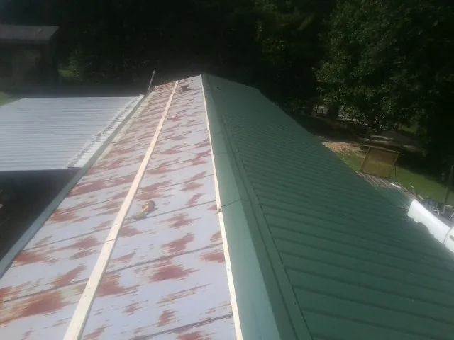Old rusted panels beside newly installed green metal roofing — Wind Damage Roof Repair by Roofing Brothers in North Miami Beach