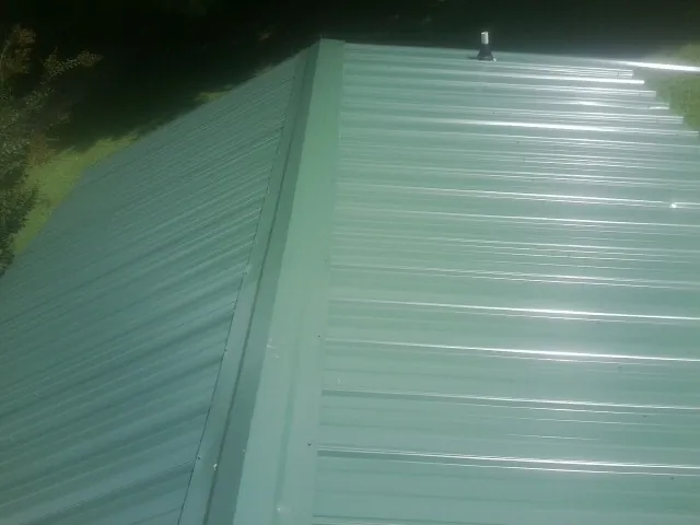 New green metal panels meeting at the ridge of a roof — Flat Roof Repair work by our crew in North Miami Beach