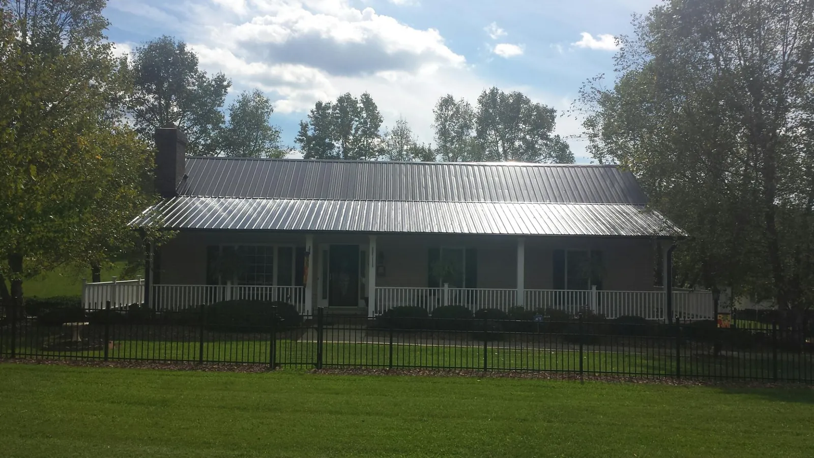 Gray metal roof on a brick ranch with a full width front porch — Gutter Guard Installation work by our crew in North Miami Beach